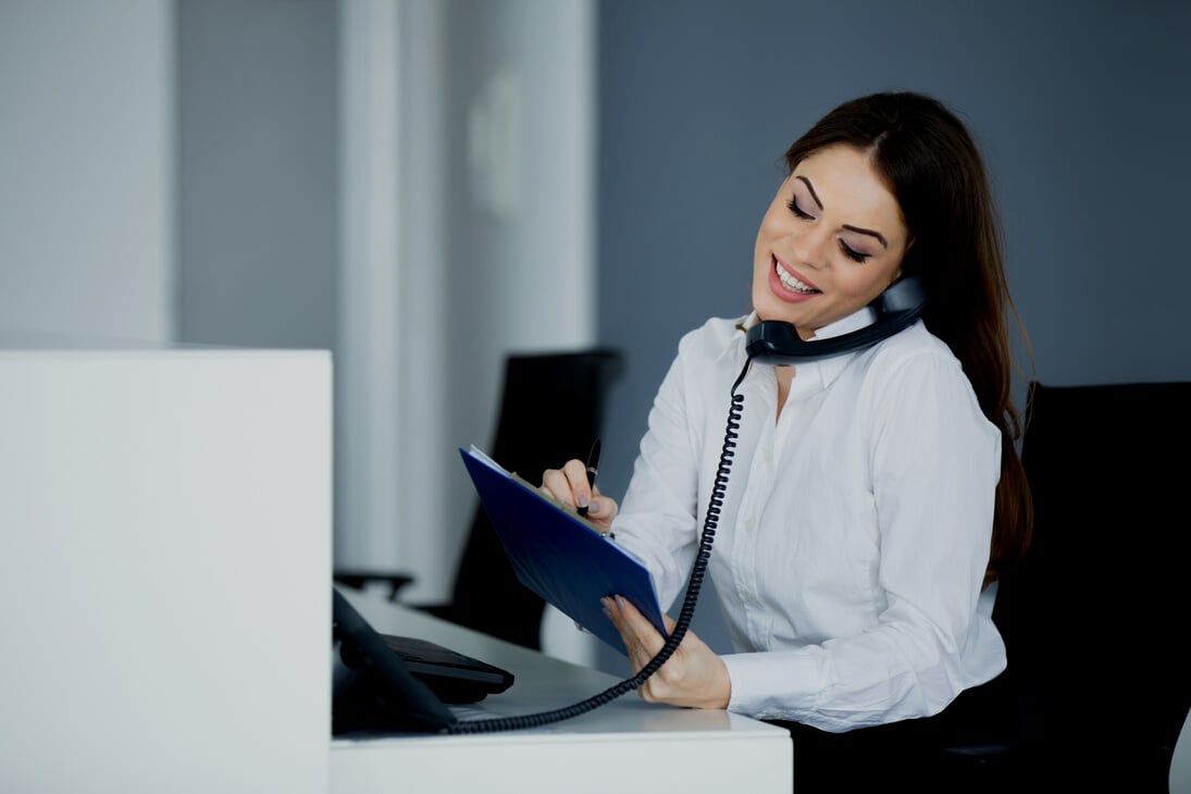 Young happy secretary talking on the phone.